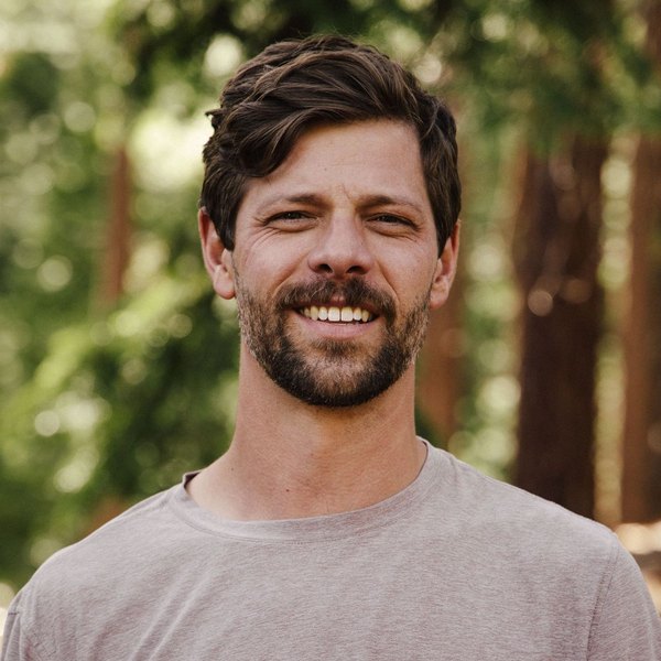 Hayden Haffey, Incline Village real estate agent, smiling in a gray t-shirt among tall trees