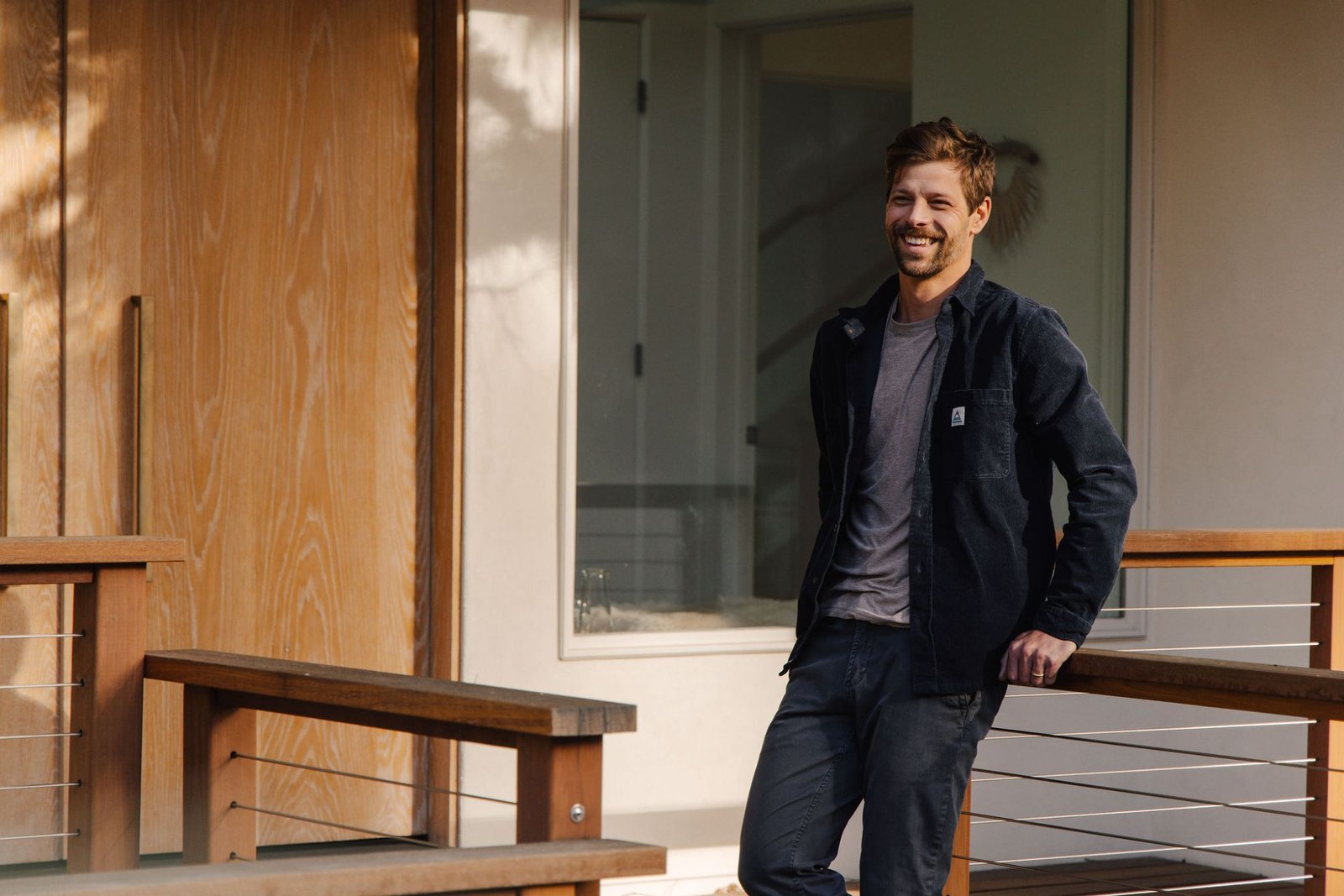 Hayden Haffey, Incline Village real estate agent with Sierra Sotheby’s International Realty, smiling as he leans on a wood and cable railing outside a modern home